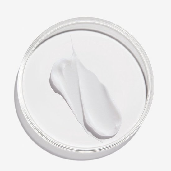 Een witte crème swatch in een petrischaal, met een dikke textuur.