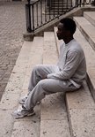 Man zittend op een trap in een grijze New Balance sweater.