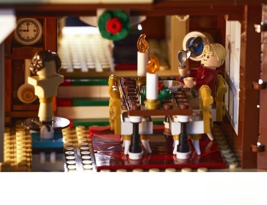 LEGO-jongen zit aan een eettafel met brandende kaarsen en eet uit een kom.