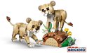Twee gele lego leeuwenwelpen, met bruine oren, op een bruine stenen ondergrond met groene planten.