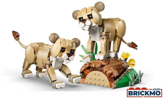 Twee gele lego leeuwenwelpen, met bruine oren, op een bruine stenen ondergrond met groene planten.