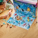 Meisje met krullend haar kijkt naar de LEGO Friends kerstkalender. Voorgrond met sneeuwpop, kerstboom en huisje.