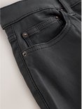 Detail van de voorkant van een zwarte skinny jeans met coating, met naden en zak.