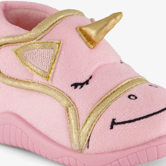 Close-up van roze pantoffel met gouden eenhoorn details en geborduurd gezicht.