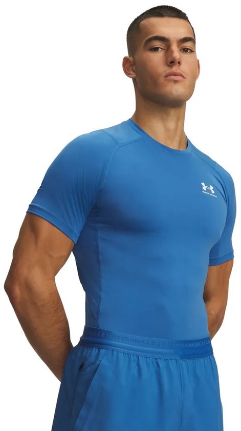 Man met gespierd bovenlichaam draagt een blauw Under Armour shirt met korte mouwen.