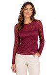 Model in donkerrode kanten top met lange mouwen en lichte broek.