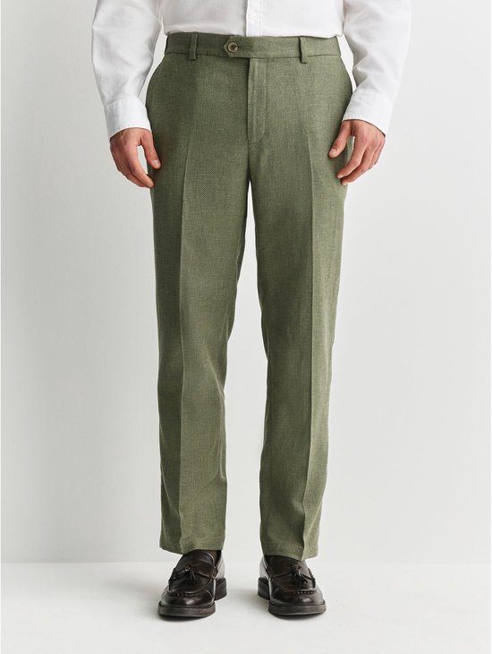 Man draagt een witte blouse en een groene, taps toelopende broek van linnenmix, van voren gezien.