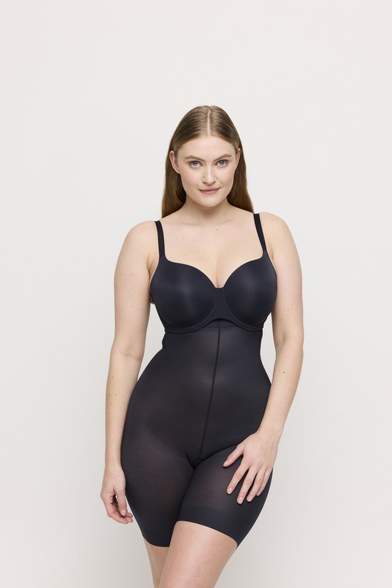 Vrouw draagt een zwarte body met shorts, met hand op haar heup.