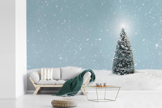 Behang - Fotobehang Een kerstboom in een besneeuwd landschap en een blauwe hemel - Breedte 525 cm x hoogte 350 cm