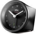 Zwarte Braun wekker met analoge wijzerplaat, witte wijzers en groene secondewijzer, van opzij gezien.
