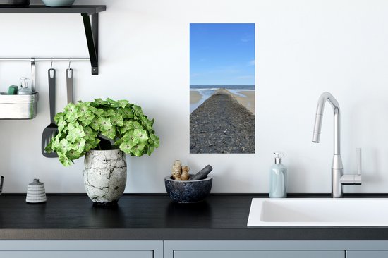 Een poster met stenen dam die naar de zee leidt, hangt boven een aanrecht.