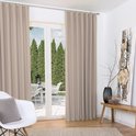 Twee beige gordijnen in een woonkamer met uitzicht op een tuin, naast een witte stoel.