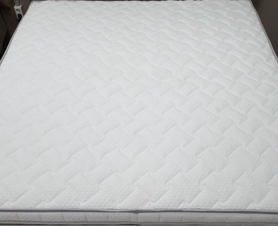 Witte hybride topper met gewatteerd oppervlak en grijze bies.