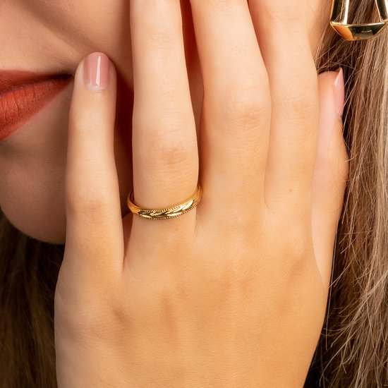 Gouden ring met delicates patroon op een vrouwelijk hand.