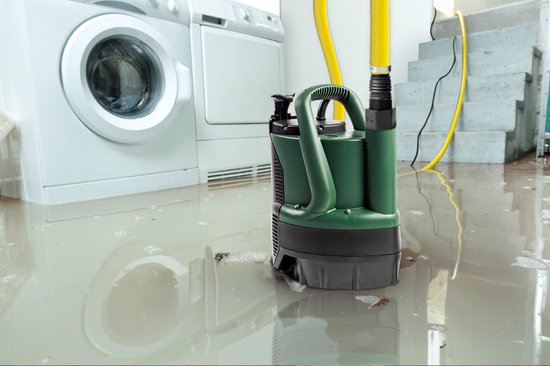 Donkergroene dompelpomp in een overstroomde wasruimte, naast een wasmachine en droger. Gele slang aangesloten.