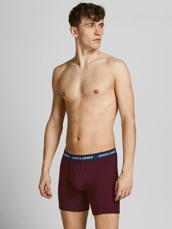 Man draagt een bordeauxrode Jack & Jones boxer met blauw logo-elastiek.