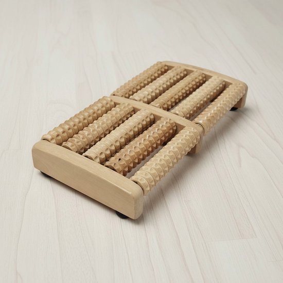 Houten voetmassage roller op een lichte houten vloer, van bovenaf gezien.
