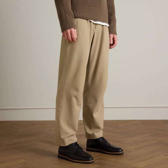 Homme en pull marron et pantalon beige, portant des chaussures basses noires à semelles marron.