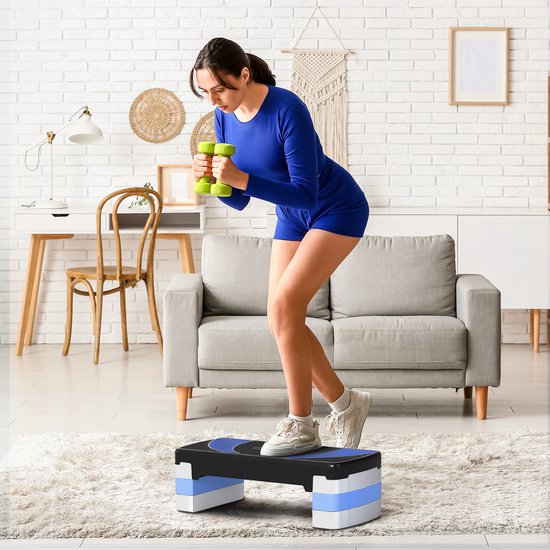 Vrouw in blauwe sportkleding traint thuis met dumbbells op een zwarte aerobic step met blauwe accenten.
