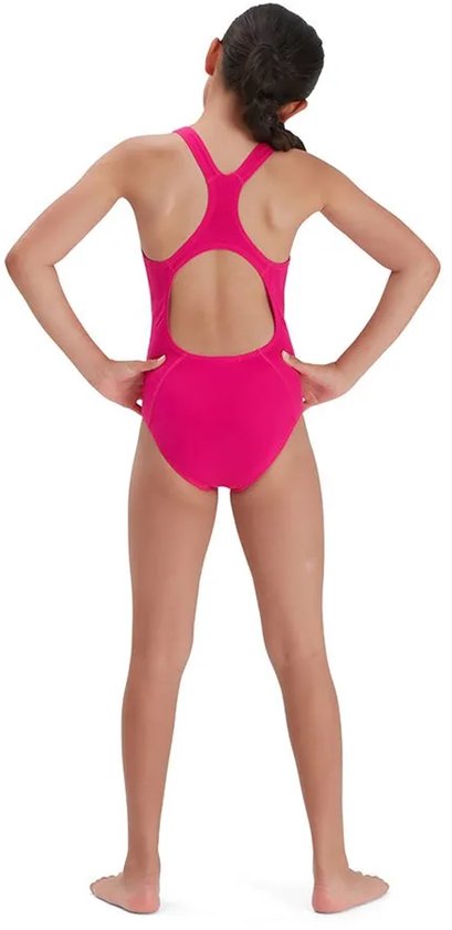 Meisje in fuchsia Speedo sportbadpak, staand met handen in de zij.