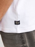 Close-up van de onderkant van een wit t-shirt met zwart label 'Petrol Industries'.