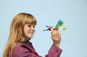 Une fille aux cheveux blonds tient un colibri LEGO coloré dans sa main.
