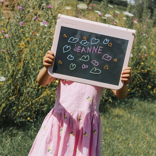 Kind met roze jurk houdt roze lichttablet met 'JEANNE' en hartjes vast in de wei.