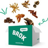 Groene BROK verpakking met verschillende hondensnacks erboven, op zwarte achtergrond.