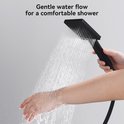 Hand houdt een zwarte vierkante handdouche vast met zachte waterstraal.