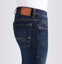 Gedetailleerde foto van de achterkant van een donkerblauwe jeans. Met oranje stiksels, een bruin label en een klein rood-wit detail op de achterzak.