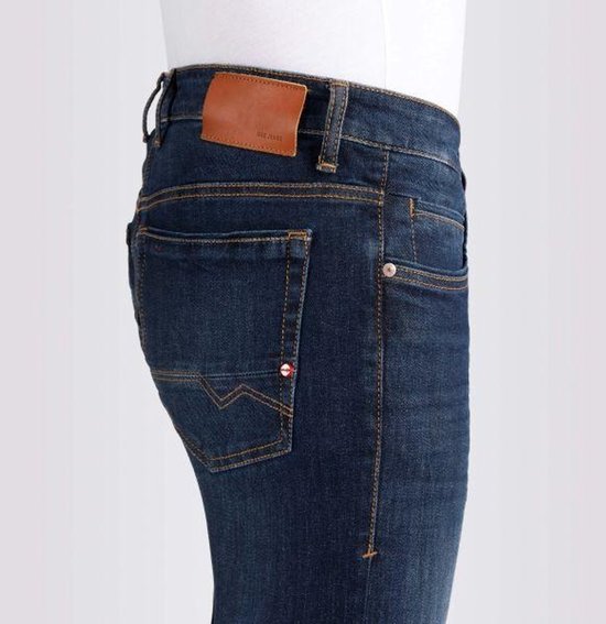 Gedetailleerde foto van de achterkant van een donkerblauwe jeans. Met oranje stiksels, een bruin label en een klein rood-wit detail op de achterzak.