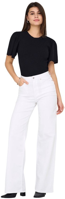 Vrouw in zwarte top met korte pofmouwen en witte wide-leg jeans, van voren gezien.