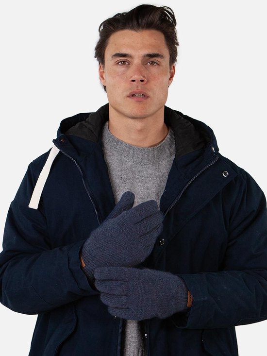 Man met donkerblauwe gebreide handschoenen en een donkerblauwe jas. Grijze trui eronder.