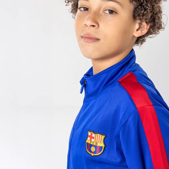 Close-up van een jongen in een blauw trainingsjack met het FC Barcelona-embleem.