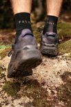 Pieds en chaussettes de randonnée FALKE noires et chaussures de randonnée bleu foncé.