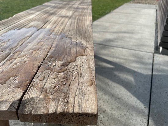 Houten bank met waterdruppels, close-up.
