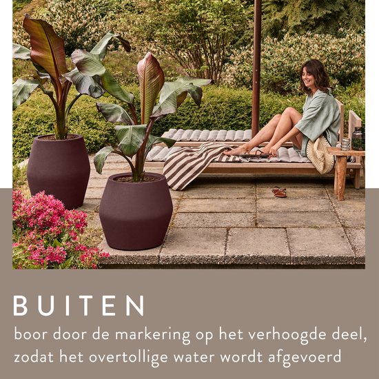 Paarse bloempotten met planten buiten op een terras met een vrouw op een ligbed.