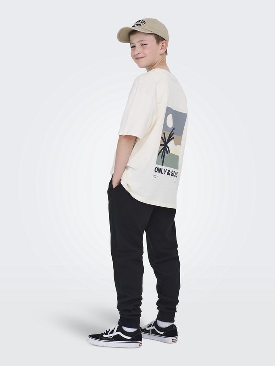 Jongen in crème T-shirt met grafische print achterkant en beige pet.