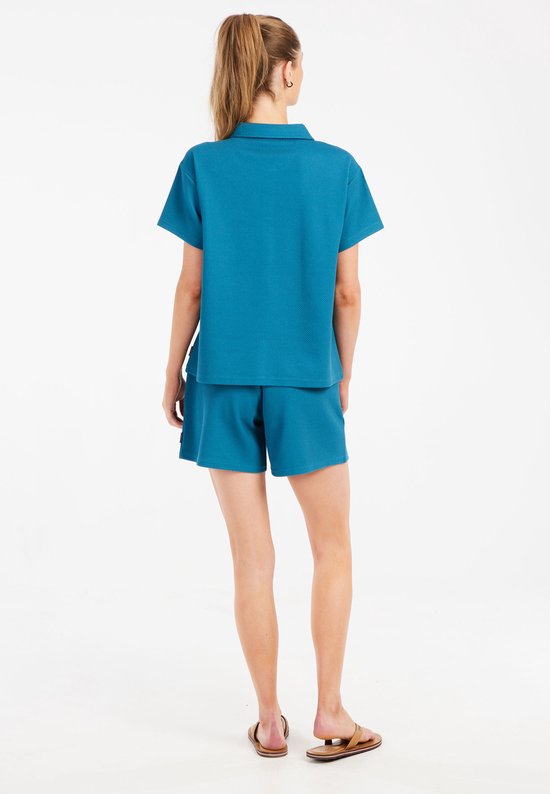 Achteraanzicht van een model met een turquoise korte broek en bijpassend shirt.