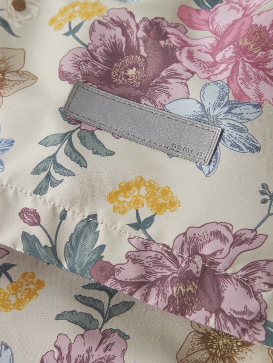 Detail van beige jas met bloemenprint en een naamlabel.