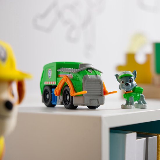 Groene Paw Patrol vuilniswagen en Rocky speelfiguur, met andere Paw Patrol speelgoed op plank.