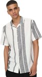 Man in wit hemd met verticale grijs-witte strepen, zwarte broek.