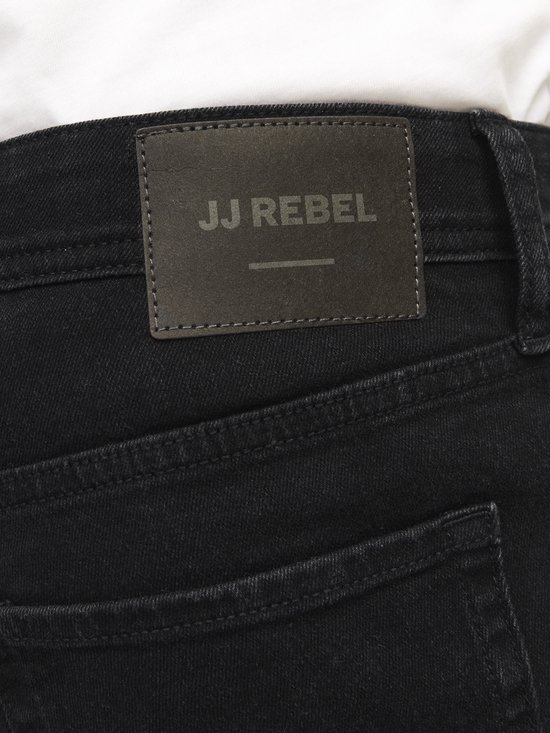 Close-up van het zwarte 'JJ REBEL' leren label op een spijkerbroek.