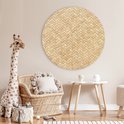 Décoration murale ronde imprimé rotin dans une chambre d'enfant avec fauteuil en rotin et peluche girafe.