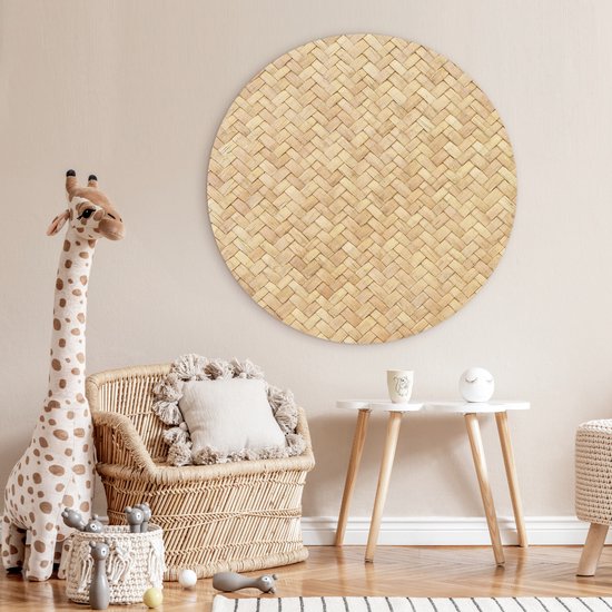Décoration murale ronde imprimé rotin dans une chambre d'enfant avec fauteuil en rotin et peluche girafe.