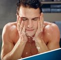 Een man wast zijn gezicht met water.