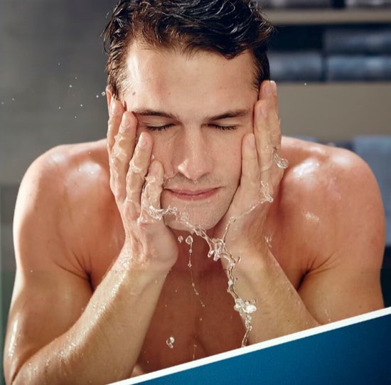 Een man wast zijn gezicht met water.