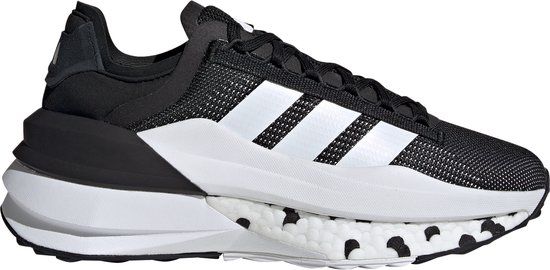 Vue latérale d'une chaussure de sport noire avec bandes Adidas blanches et semelle blanche à pois noirs.