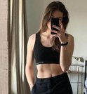 Jong model neemt spiegel selfie in zwarte nauwsluitende crop top en zwarte broek.