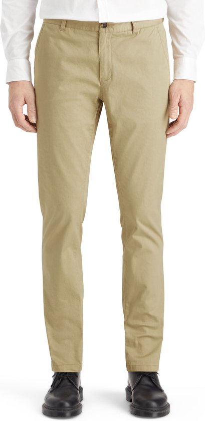 Man in beige chino broek, witte overhemd en zwarte schoenen.